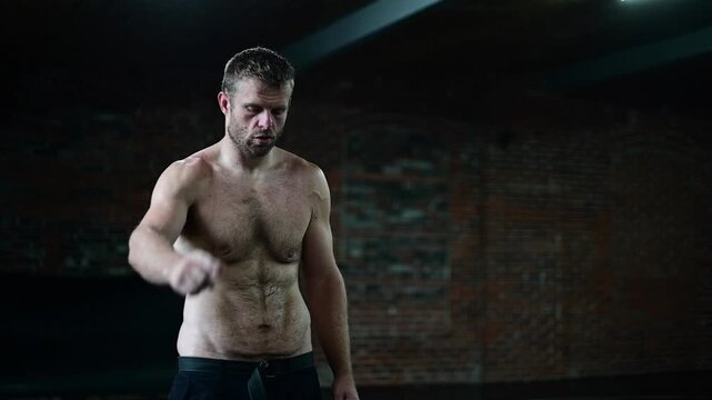 Dark lit gym 120 frames per second video, man in shape shadow boxing, soft focus b roll video, background bokeh, boxing mma workout