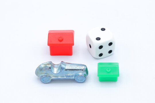 Monopoly game pieces. Car, red hotel, green house and dice. Different tokens, close up and isolated. Home concept.