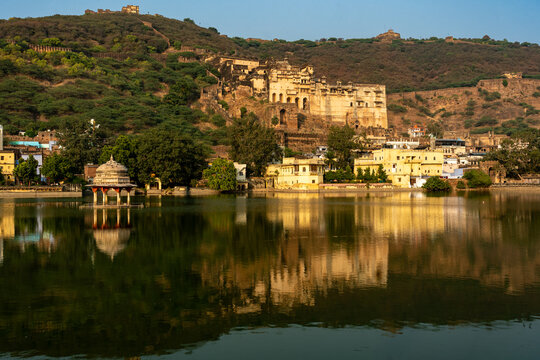 India. Rajasthan. Bundi. Garh Palace, nestled against the fortified hill of Taragarh, is reflected in the waters of Lake Nawal Sagar