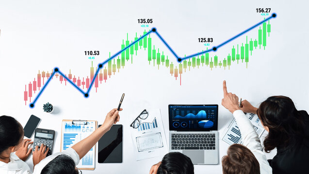 Business professionals analyzing financial data and charts, discussing stock market trends and performance metrics in a modern office environment. Quark.