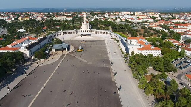 Majestic aerial view of the sanctuary of fatima in portugal, showcasing the vast plaza where pilgrims gather and the impressive basilica of our lady of the rosary under a clear blue sky