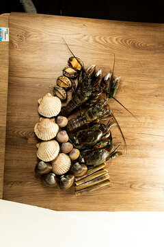 Fresh seafood displayed on a wooden table featuring various shellfish and crustaceans