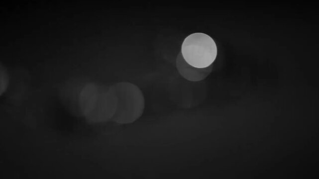Monochrome silver bokeh light circles glowing on dark abstract video background