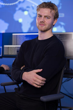 Confident young professional male in control room monitoring systems and data