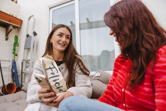 Two female friends talking together at a birthday party on an apartmen