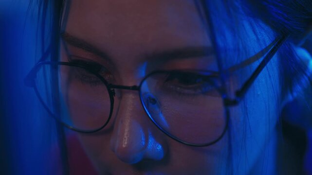 Woman wearing glasses portrait with blue light across face closeup, dark hair reflection, calm expression, closed eye, moody dramatic studio mood