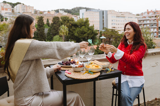 Two female friends clinking drinks at a birthday party on an apartment