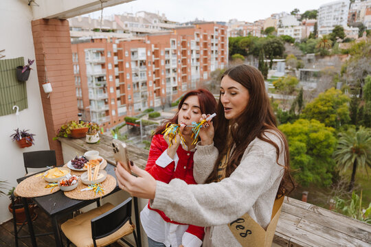 Two female friends taking selfie at a birthday party on an apartment b