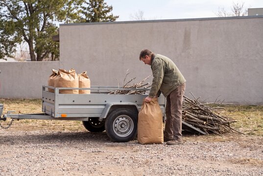 Gardener placing organic waste bag into utility trailer