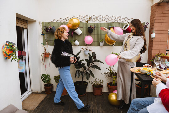 Two female friends holding balloons at a birthday party on an apartmen