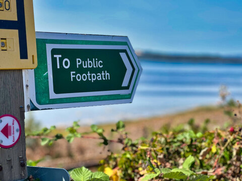Green Public Footpath Sign with Arrow Along Coastal Walking Trail in Devon, UK