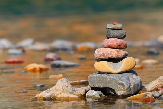 balancing Zen stones on the shore of a body of water