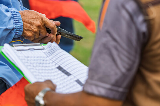 Referee checking starting pistol revolver for sports competition. 
Sports official holding revolver starting pistol, checking cylinder and blank ammunition before initiating a race. Selective focus.