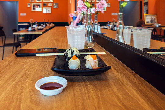 Japanese sushi plate on wooden bar counter with mirror reflection. Fresh assorted sushi with chopsticks on wooden counter bar, featuring mirror reflects interior atmosphere of Japanese restaurant.