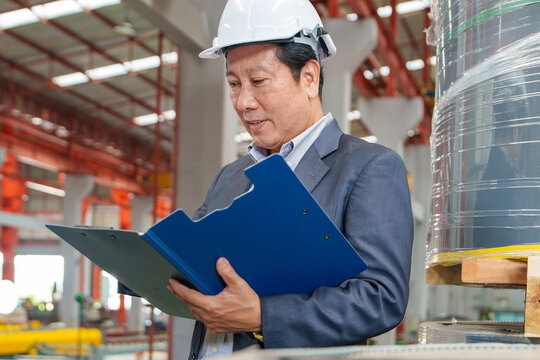 Manager Reviewing Quality Control Documentation in Manufacturing Environment for Project Management and Industrial Reporting