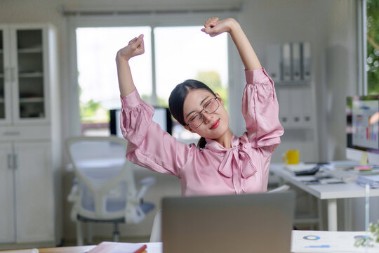 Woman stretching at office desk taking a break from work