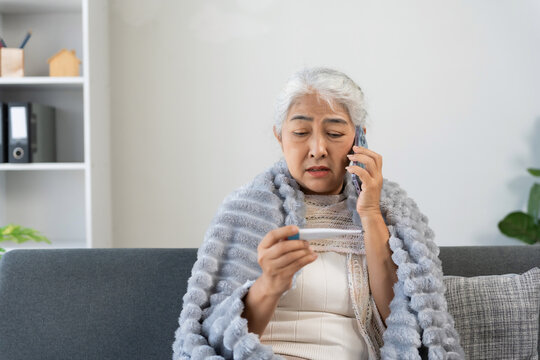 Senior woman teleconsulting doctor about fever holding thermometer