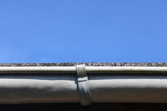 Gutter system on house roof against clear blue sky