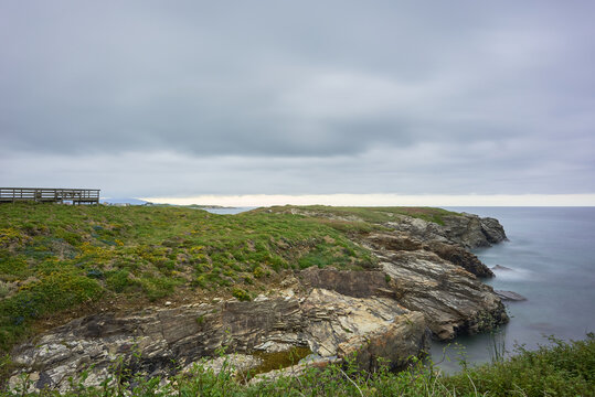 Moody long exposure of misty sea and rock at Praia das Catedrais, Beach of the Cathedrals in Ribadeo, Galicia Spain