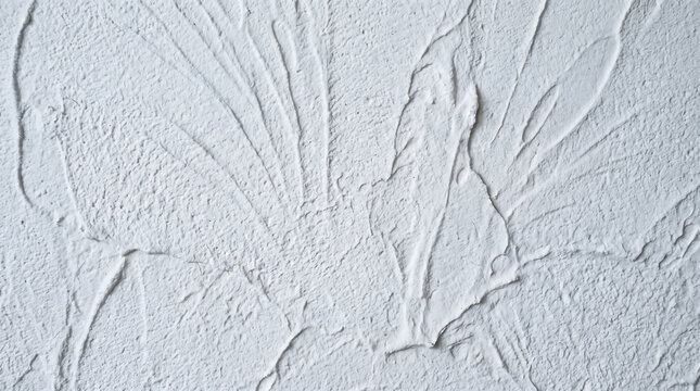 Plaster wall surface features a decorative white textured pattern with raised swirling lines and ridges.