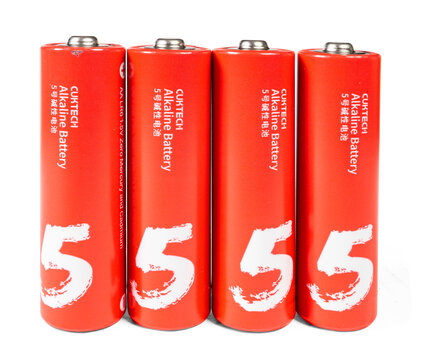 Four bright red Cuktech AA alkaline batteries standing in a row isolated on a clean white background