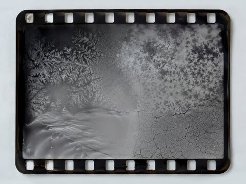 Vintage 35mm film strip frame with ice frost crystals and cracked emulsion texture abstract design