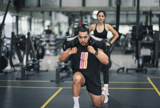 Man doing lunges with weighted bag in gym