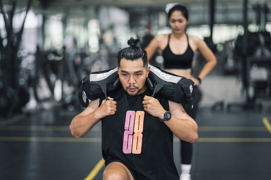 Man doing lunges with weighted bag in gym