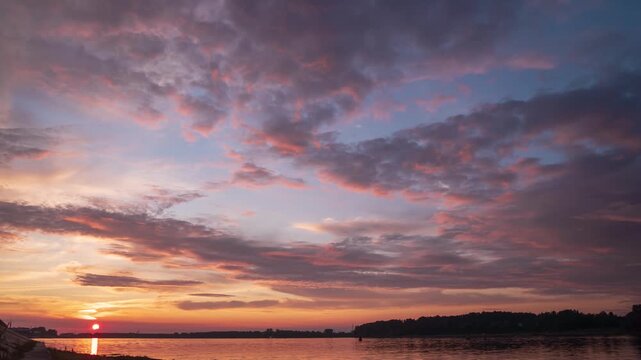 Scenic view of beautiful sunset or sunrise above the pond or lake at spring or early summer evening with cloudy sky background  Landscape. Water reflection. 
