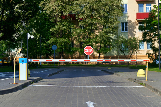 Automatic parking barrier gate and security surveillance camera controlling entry to residential neighborhood. Boom gate arm with cctv camera restricting vehicle access to private parking area