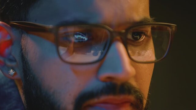 Serious pensive Indian business man male in glasses with reflected graph reflection talking thinking talk video call Arabian businessman male look in computer data analytics diagram at night evening