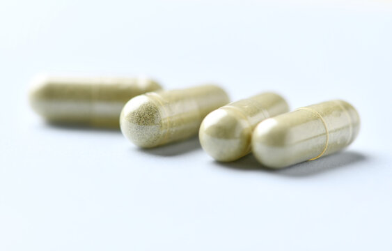 Barley grass capsules. Antioxidants. Concept for a healthy dietary supplementation. Bright background. Soft focus. Close up. Copy space.