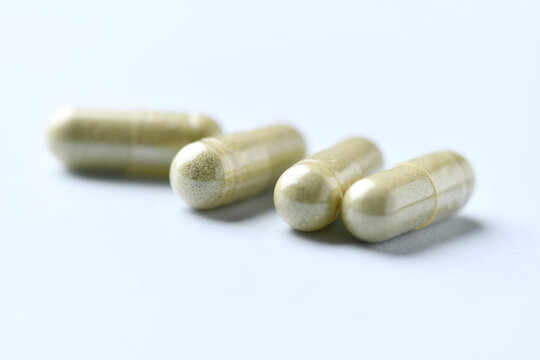 Barley grass capsules. Antioxidants. Concept for a healthy dietary supplementation. Bright background. Soft focus. Close up. Copy space.