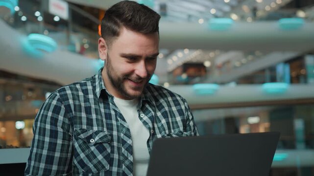 Pensive Caucasian man businessman thinking with laptop come up with idea in business center guy male freelancer user think with computer finding answer working remote chatting online in shopping mall