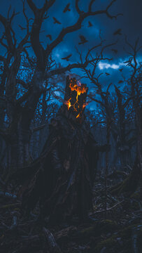 Halloween witch with burning head stands in dark forest