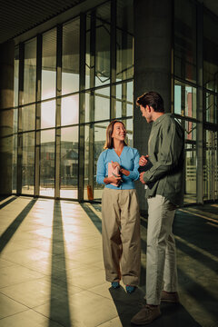 Business colleagues discussing project ideas in modern glass office building during sunset