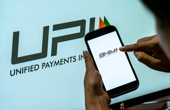 In this photo illustration, A person uses a smartphone displaying the BHIM Pay logo against a prominent UPI, Unified Payments Interface, backdrop