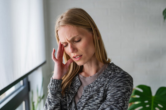 Tired woman holding her forehead after a demanding day. Fatigue, overwork, exhaustion, stress, low energy and recovery from physical or mental strain
