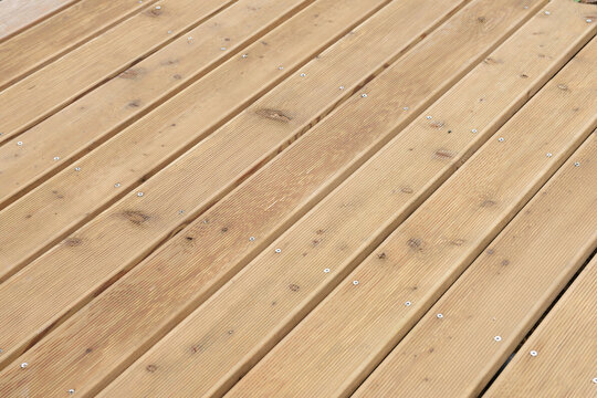 High angle perspective view of wooden terrace decking boards background. Natural wood plank surface texture with screws, suitable for outdoor patio, balcony, or flooring concepts.