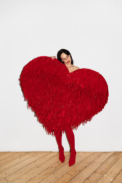 Woman holding large red heart shape covering body