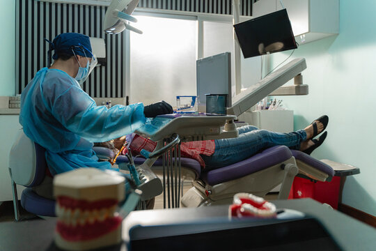 Dental professional wearing protective gear assisting patient