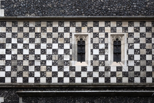 Chequerboard stone pattern on medieval church wall with small windows for use as a background texture