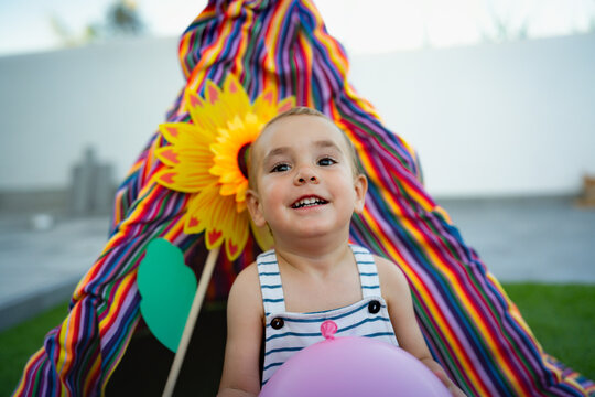 Toddler boy smiling holding balloon at colorful teepee party