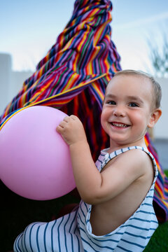 Happy little boy playing with pink balloon outdoors