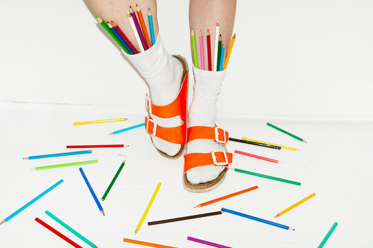 Person wearing fashion style sandals & sock full of colour art pencils