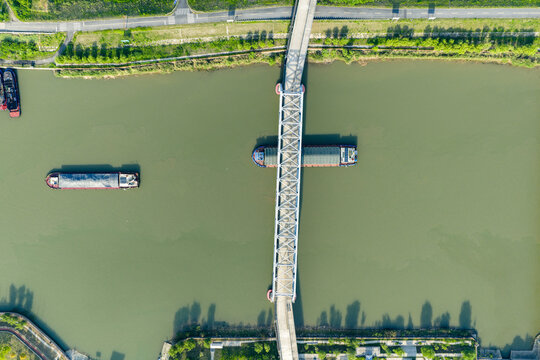 highway bridge over river with cargo barges passing below