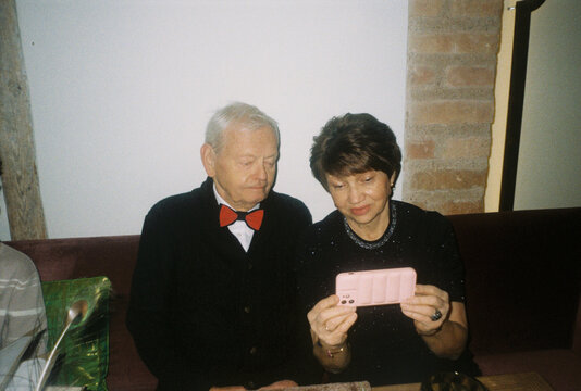 Senior Couple in Festive Attire Looking at Cellphone