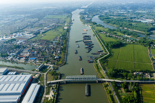 highway bridge over river with cargo barges passing below