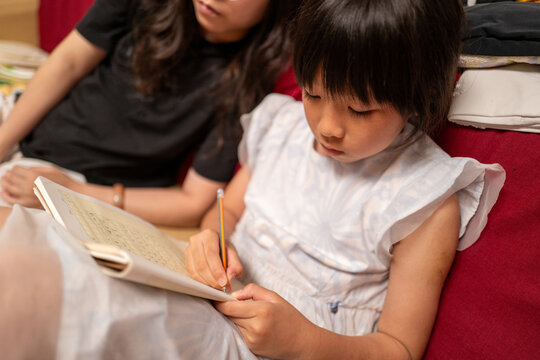 Child Writes in Notebook While Sitting on Couch in a Home Setting