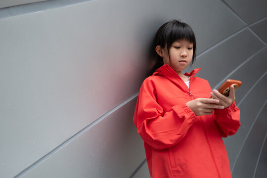 Girl Using Smartphone While Leaning Against a Wall